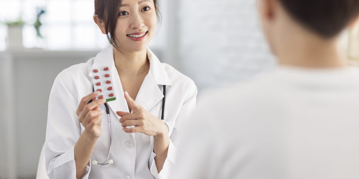 Doctor is pointing to drug tablet and introducing to patient.