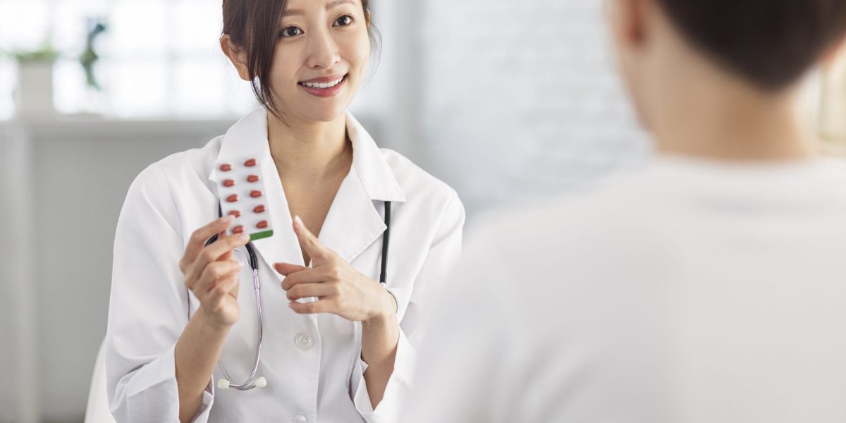 Doctor is pointing to drug tablet and introducing to patient.